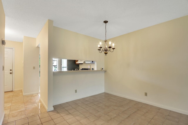 spare room with a notable chandelier and light tile patterned floors