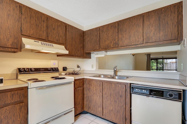 kitchen with a textured ceiling, sink, white appliances, and light tile patterned floors