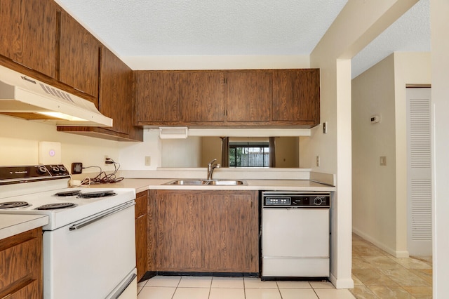 kitchen with a textured ceiling, sink, white appliances, and light tile patterned floors