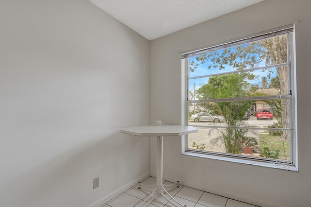 spare room featuring light tile patterned flooring, plenty of natural light, and a textured ceiling