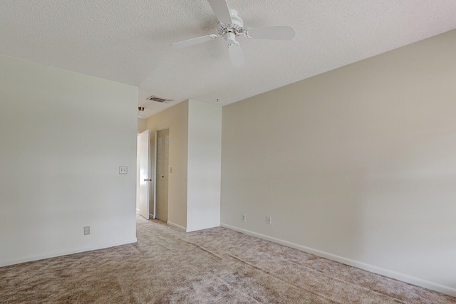 spare room with ceiling fan, a textured ceiling, and light carpet