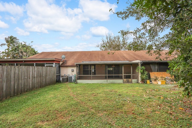 rear view of house with a lawn, central AC, and a sunroom