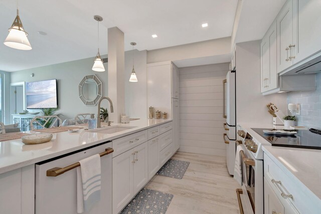 kitchen featuring a kitchen bar, white appliances, pendant lighting, white cabinets, and sink