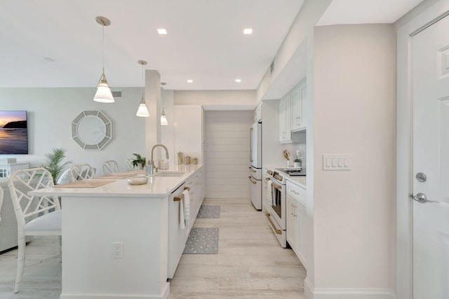 kitchen with white cabinetry, hanging light fixtures, a breakfast bar, sink, and white appliances