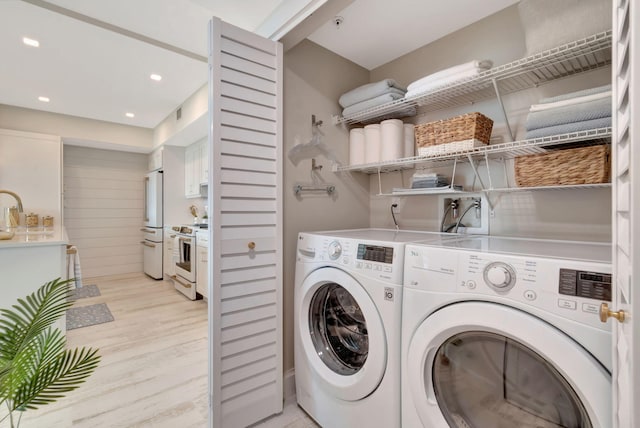 laundry area with washer and dryer, sink, and light wood-type flooring