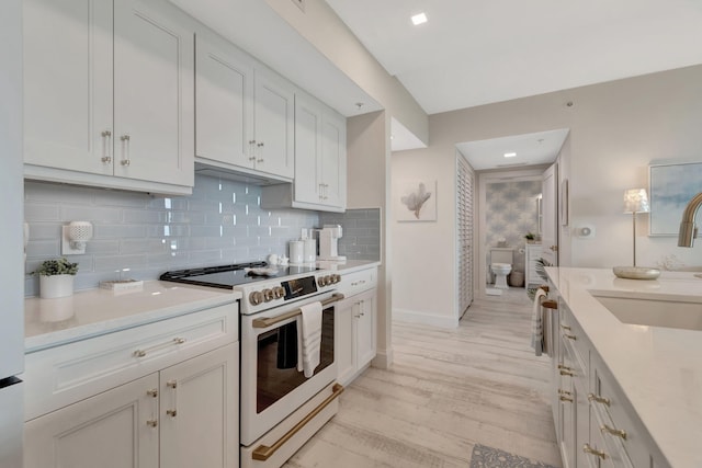 kitchen with sink, white electric range oven, and white cabinetry