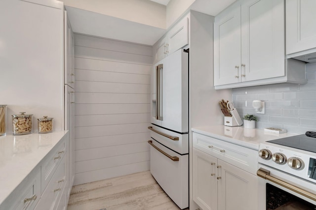 kitchen featuring high end white fridge, white cabinetry, electric range, and backsplash