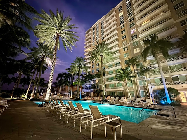 pool at dusk with a patio area