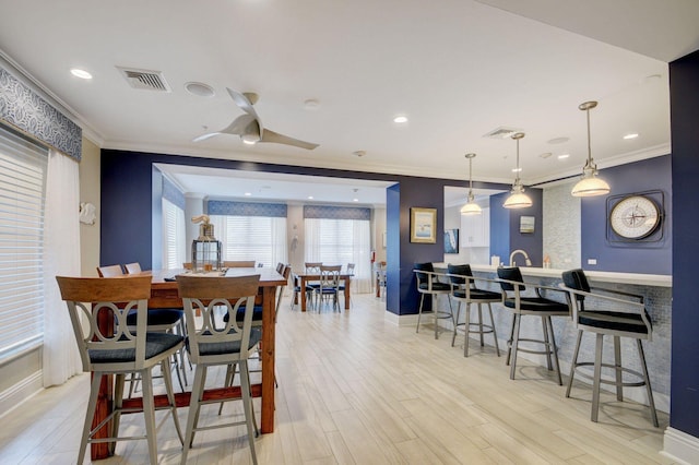 dining area featuring ceiling fan, crown molding, and light hardwood / wood-style floors