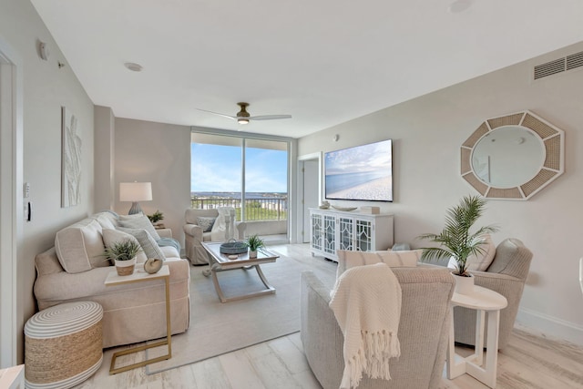 living room featuring ceiling fan, light hardwood / wood-style flooring, and expansive windows