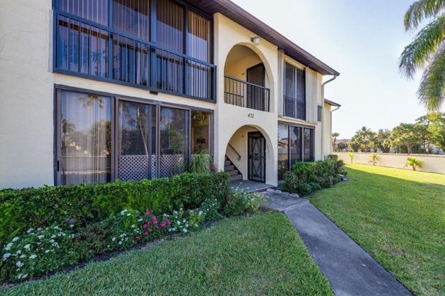 property entrance with a lawn and a balcony