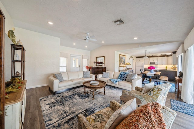 living room featuring dark wood-type flooring, ceiling fan, a textured ceiling, and lofted ceiling