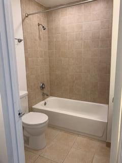 bathroom featuring toilet, tiled shower / bath, and tile patterned floors