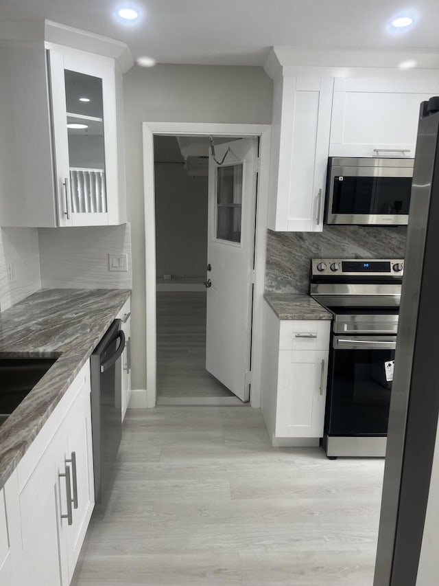 14910 Wildflower Ln, Delray Beach, FL 33446 - kitchen with stainless steel appliances, dark stone counters, light wood-style floors, white cabinetry, and recessed lighting