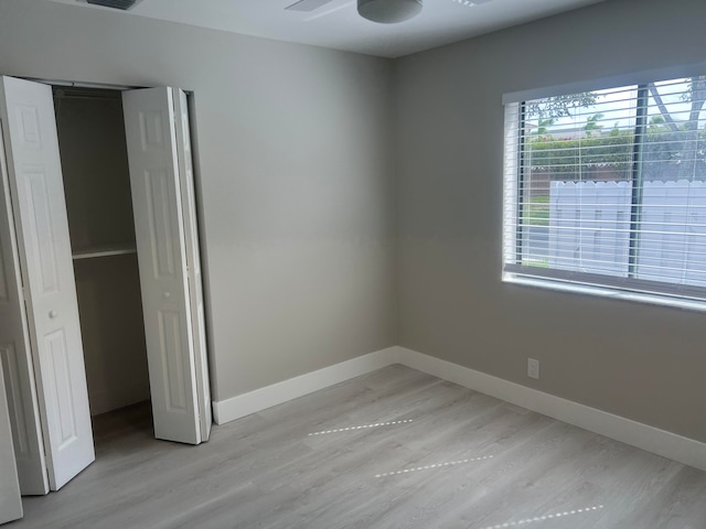 unfurnished bedroom featuring light hardwood / wood-style flooring, a closet, and ceiling fan