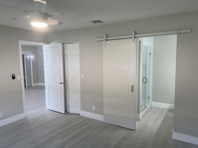 14910 Wildflower Ln, Delray Beach, FL 33446 - unfurnished bedroom featuring wood finished floors, baseboards, a barn door, and a ceiling fan