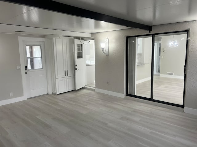 interior space featuring beam ceiling and light hardwood / wood-style flooring