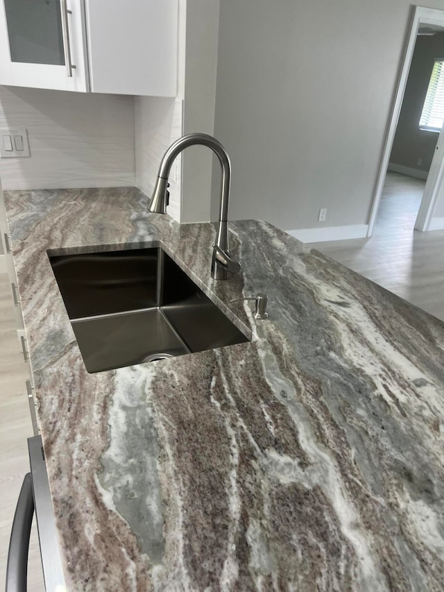 details with sink, light hardwood / wood-style flooring, dark stone counters, and white cabinets