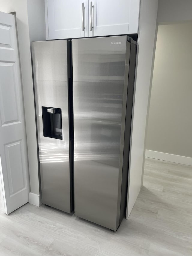 14910 Wildflower Ln, Delray Beach, FL 33446 - kitchen view of stainless steel refrigerator with ice dispenser, white cabinetry, light wood finished floors, and baseboards