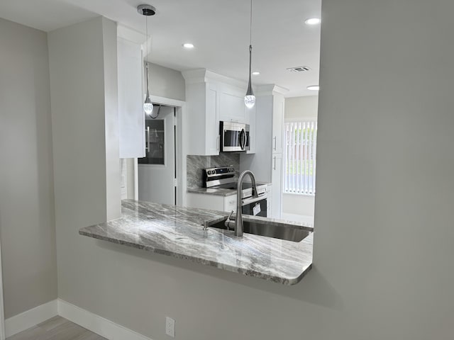 14910 Wildflower Ln, Delray Beach, FL 33446 - kitchen with stainless steel appliances, a sink, white cabinetry, light stone counters, and decorative backsplash