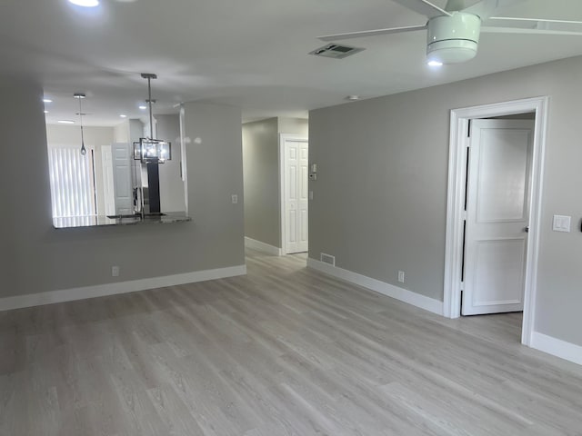 unfurnished living room featuring an inviting chandelier and light wood-type flooring