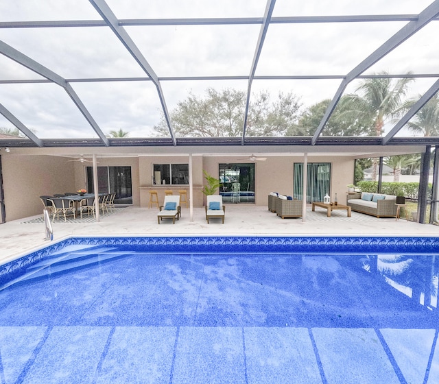 view of pool featuring an outdoor living space, glass enclosure, a patio, and ceiling fan