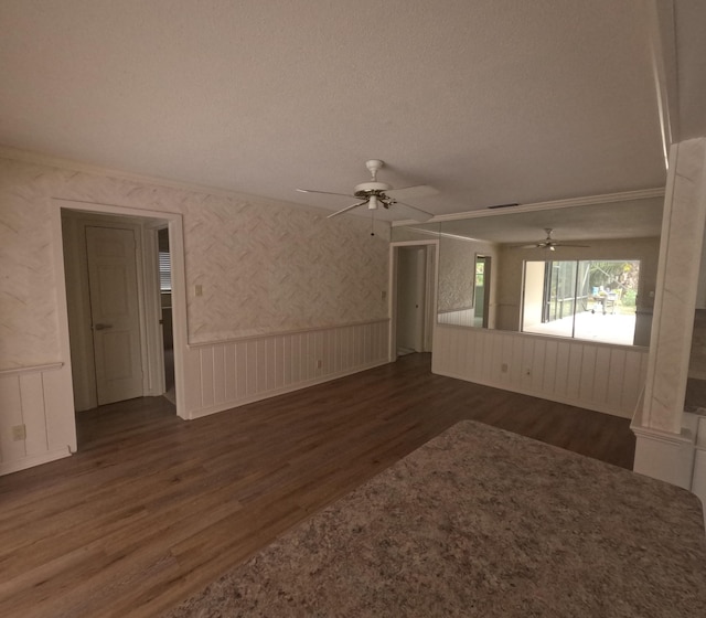 unfurnished living room with a textured ceiling, crown molding, ceiling fan, and dark wood-type flooring