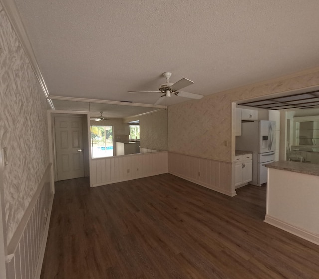 unfurnished living room with a textured ceiling, dark hardwood / wood-style flooring, ceiling fan, and crown molding