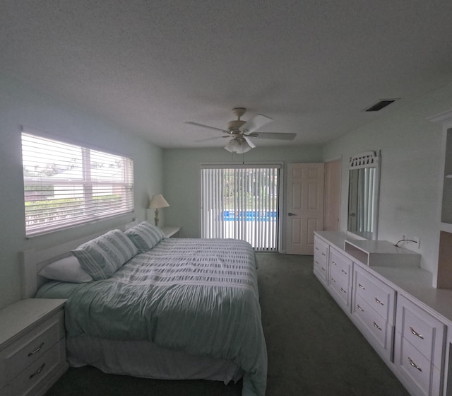 bedroom with access to exterior, a textured ceiling, dark carpet, and ceiling fan