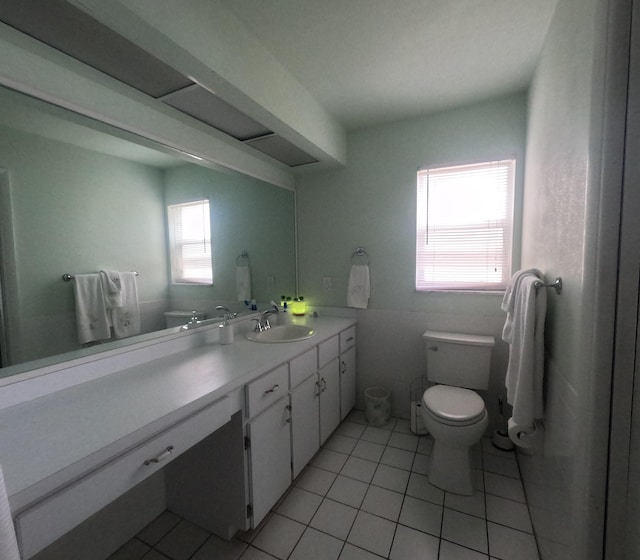 bathroom with toilet, vanity, tile patterned floors, and a healthy amount of sunlight