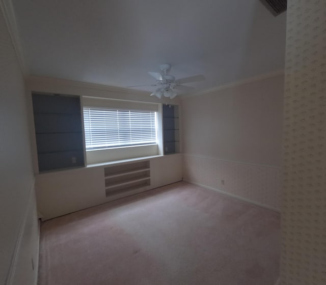 unfurnished room featuring light carpet, ceiling fan, and crown molding