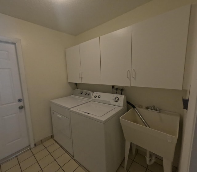 clothes washing area featuring washer and dryer, light tile patterned flooring, cabinets, and sink