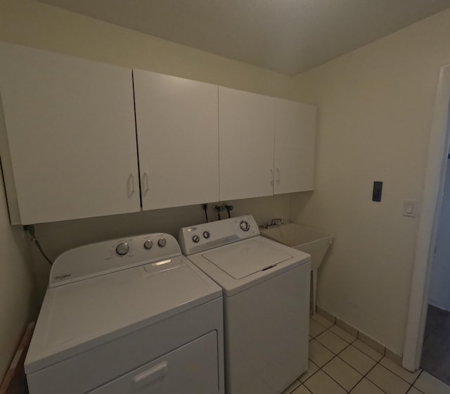 laundry room with washer and clothes dryer, light tile patterned flooring, cabinets, and sink