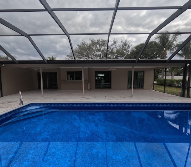 view of swimming pool with a patio, glass enclosure, and ceiling fan