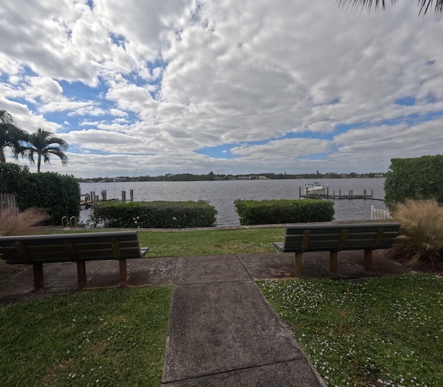 view of community featuring a lawn, a boat dock, and a water view