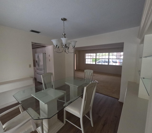 dining room featuring dark hardwood / wood-style flooring, a textured ceiling, and a chandelier