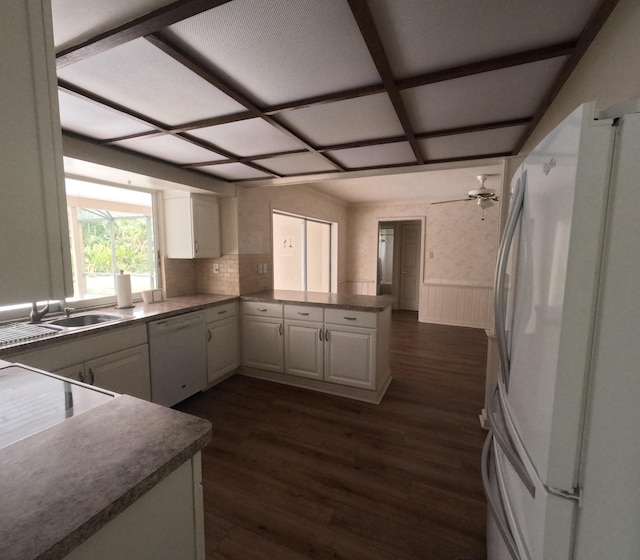 kitchen with dark hardwood / wood-style flooring, backsplash, kitchen peninsula, white appliances, and white cabinets