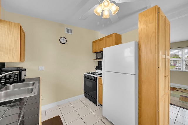 kitchen with light brown cabinets, sink, black appliances, light tile patterned floors, and ceiling fan