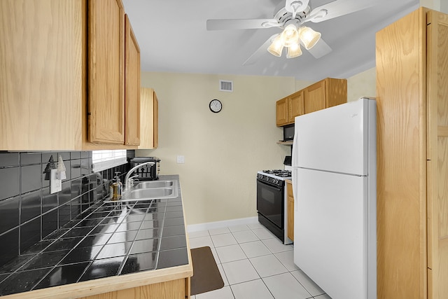 kitchen with decorative backsplash, tile counters, sink, white refrigerator, and gas stove