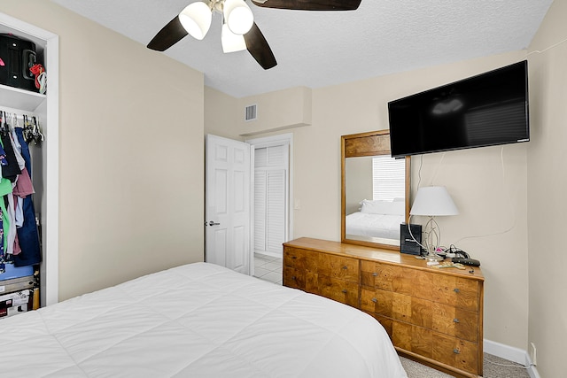 carpeted bedroom with a textured ceiling, a closet, and ceiling fan