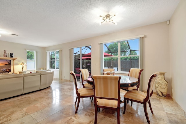 dining area featuring a notable chandelier, a textured ceiling, and a healthy amount of sunlight