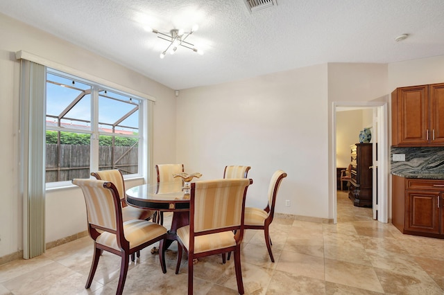 dining area with a textured ceiling and an inviting chandelier