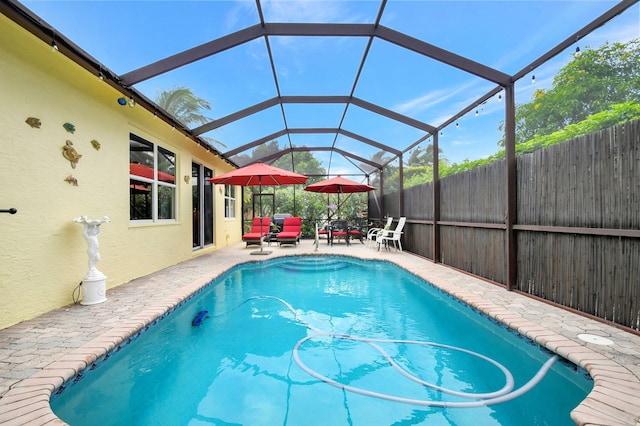 view of swimming pool with a patio area and a lanai