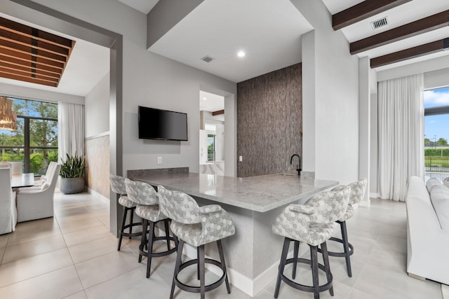 kitchen with beam ceiling, a wealth of natural light, and kitchen peninsula