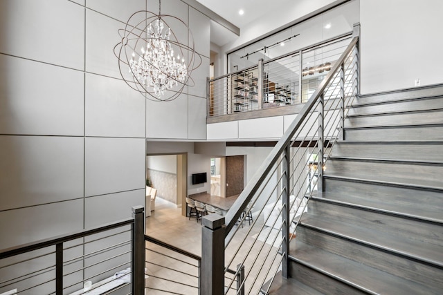 staircase with a notable chandelier and track lighting