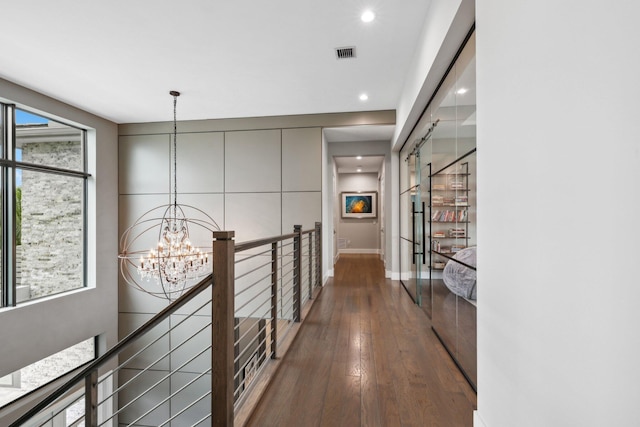 corridor featuring hardwood / wood-style floors, a chandelier, and plenty of natural light