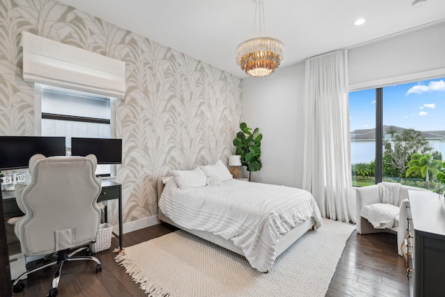 bedroom featuring dark wood-type flooring, a notable chandelier, and a water view