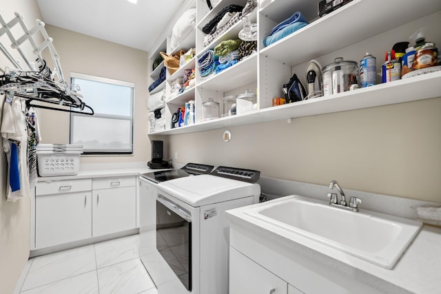 clothes washing area featuring sink, washer and dryer, and cabinets