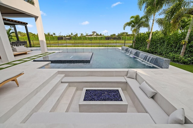 view of swimming pool featuring a patio area, pool water feature, and an outdoor living space with a fire pit