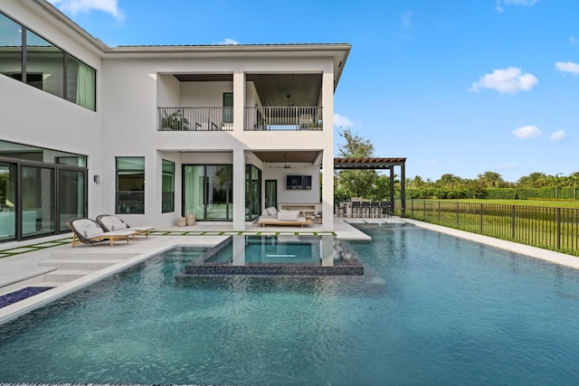 back of house with an outdoor hangout area, ceiling fan, a patio, a swimming pool with hot tub, and a balcony